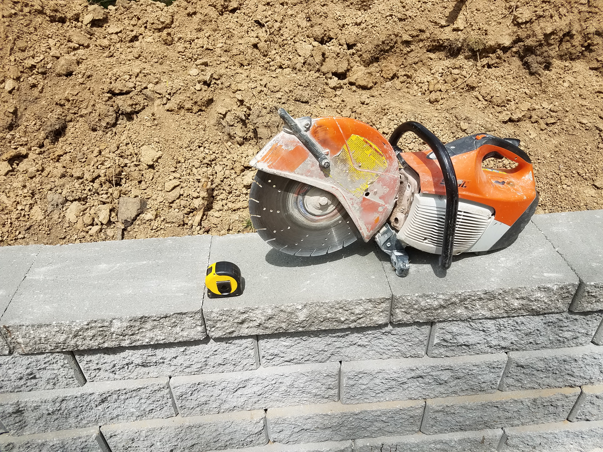 Tools used for building a retaining wall displayed on top of a finished wall by Greenstone Landscaping in St. Louis County.